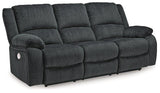 Ashley Furniture Draycoll power reclining sofa with plush cushions and dark upholstery, shown in a modern living room setting.