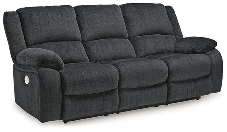 Ashley Furniture Draycoll power reclining sofa with plush cushions and dark upholstery, shown in a modern living room setting.