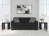 Ashley Furniture Jasmine Peaks Sofa with plush fabric and modern design, featuring cushioned armrests and decorative throw pillows.