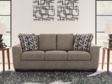 Ashley Furniture Triston-Peaks sofa with plush cushions and neutral fabric, shown in a cozy living room setting.