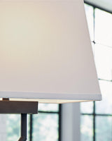 Pair of Ashley Furniture Brookthrone table lamps with beige fabric shades and dark wood bases, set on a wooden table.