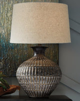 Ashley Furniture Magan Table Lamp with a sleek design, featuring a modern base and a fabric lampshade, ideal for living room decor