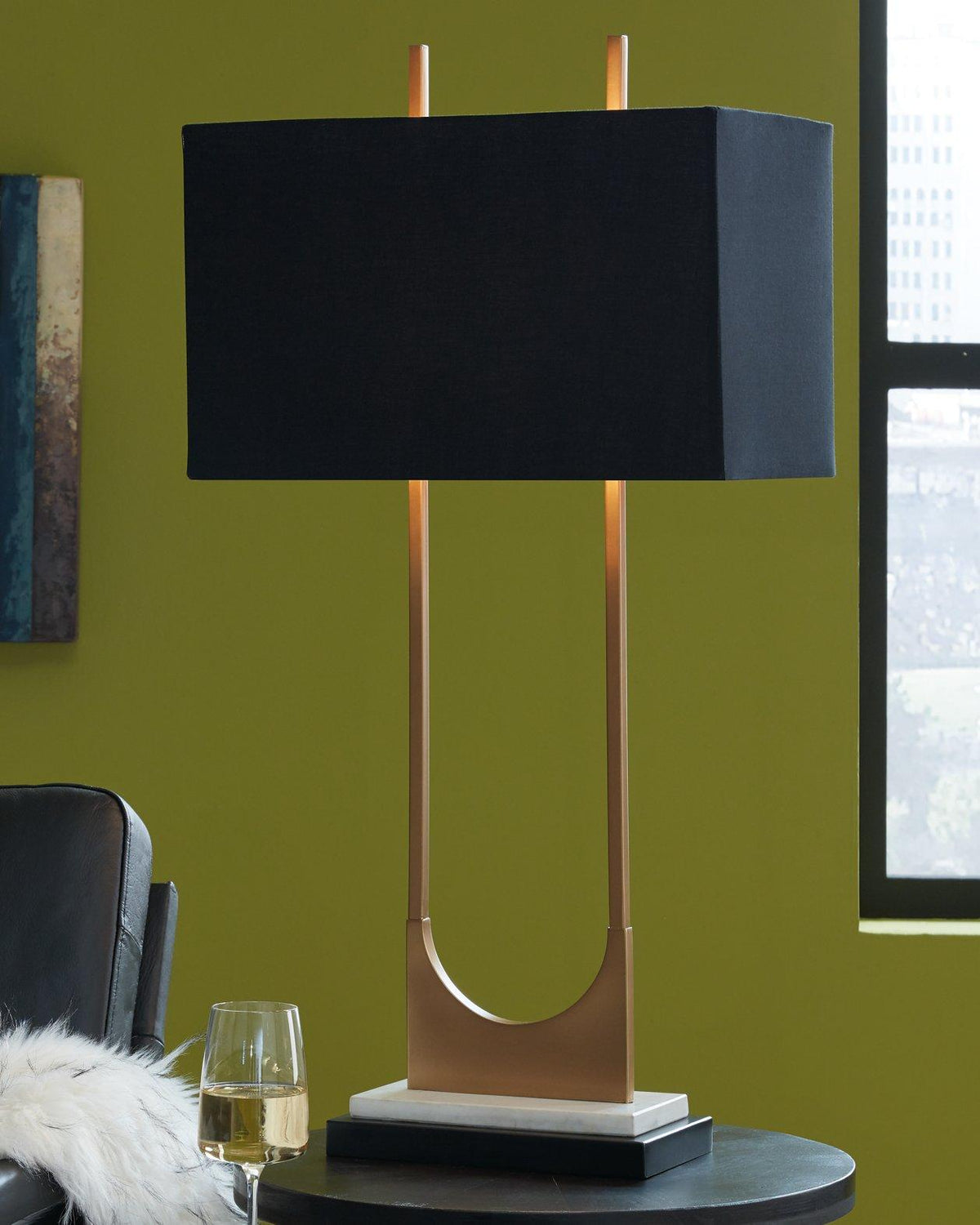 Malana table lamp by Ashley Furniture featuring a modern design with a neutral fabric shade and sleek base.