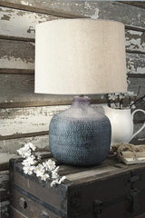 Malthace table lamp with a sleek base and fabric shade, designed by Ashley Furniture, placed on a wooden side table.