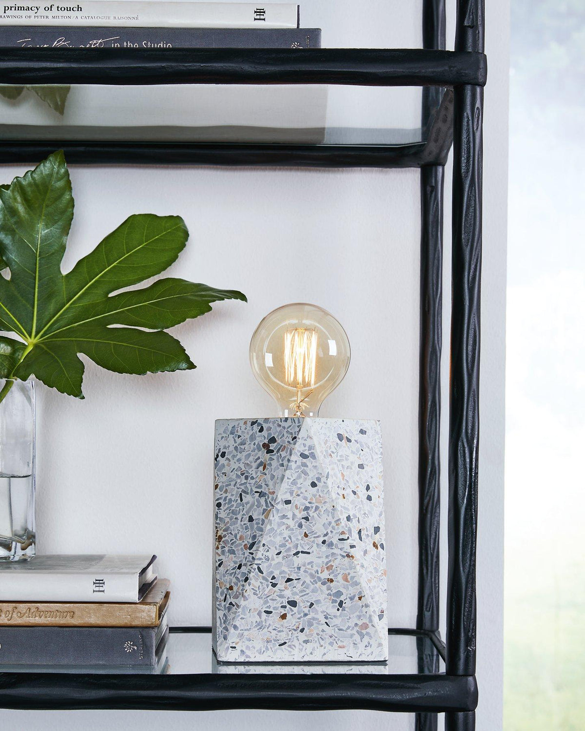Maywick table lamp by Ashley Furniture, featuring a sleek design with a fabric shade and modern base on a wooden side table.