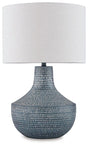 Schylarmont Table Lamp by Ashley Furniture featuring a sleek ceramic base and fabric shade on a wooden bedside table