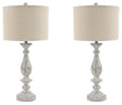 Pair of Ashley Furniture Bernadate table lamps with beige fabric shades and ceramic bases on a wooden surface.