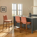 Orange upholstered MCM-style barstool by Article with walnut wooden legs, designed for counter seating.