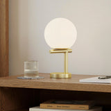 Gold MCM Table Lamp by Article with sleek modern design and a smooth, curved base in a well-lit interior setting