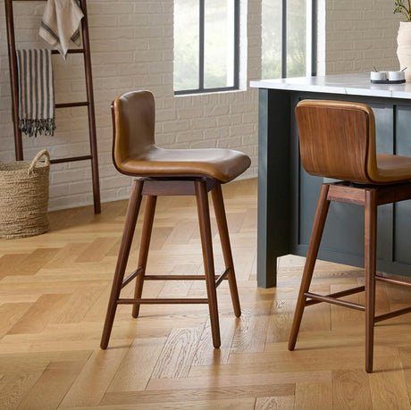 Leather swivel counter stool by Article with tan leather seat and walnut wooden legs, showcasing a modern barstool design.