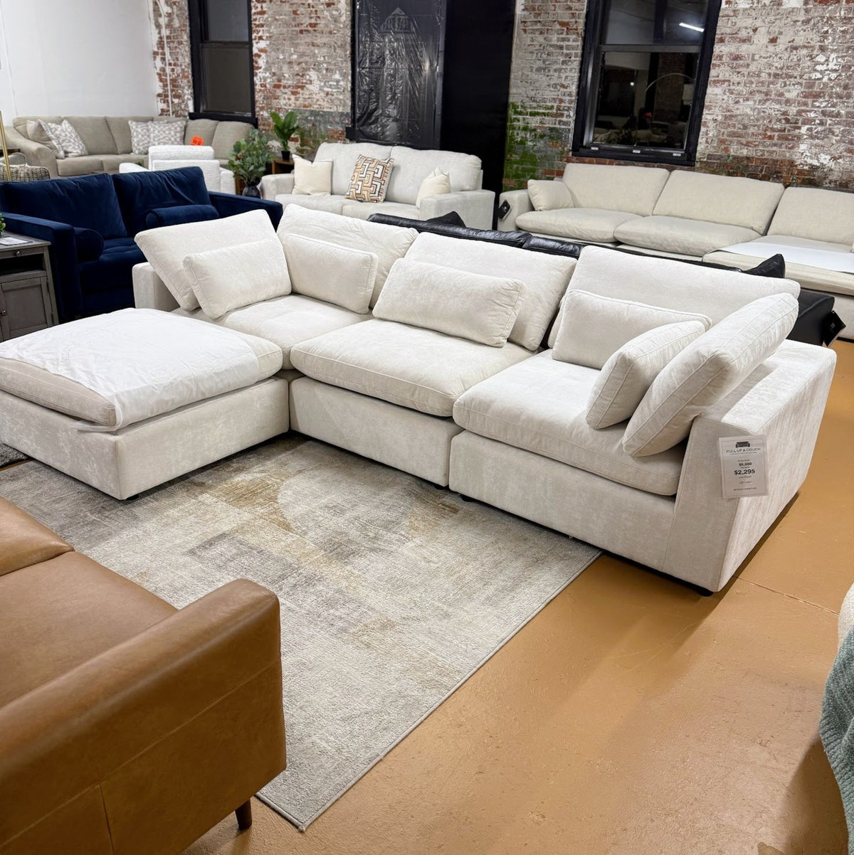 Pull Up A Couch Serenity Cloud sectional with storage ottoman, featuring plush fabric, multiple seats, and built-in storage in a modern design.